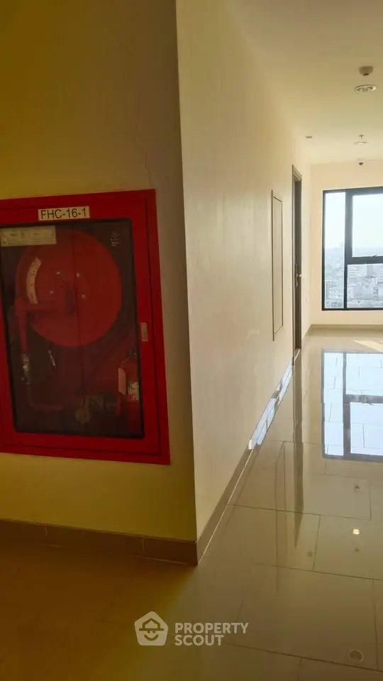 Bright corridor with fire safety equipment and city view window.