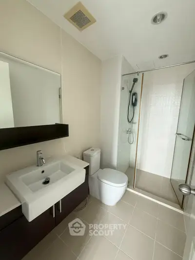 Modern bathroom with sleek fixtures and glass shower enclosure in a contemporary apartment.