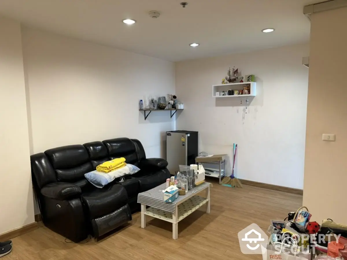 Cozy living room with black leather sofa and wooden flooring, perfect for relaxation.