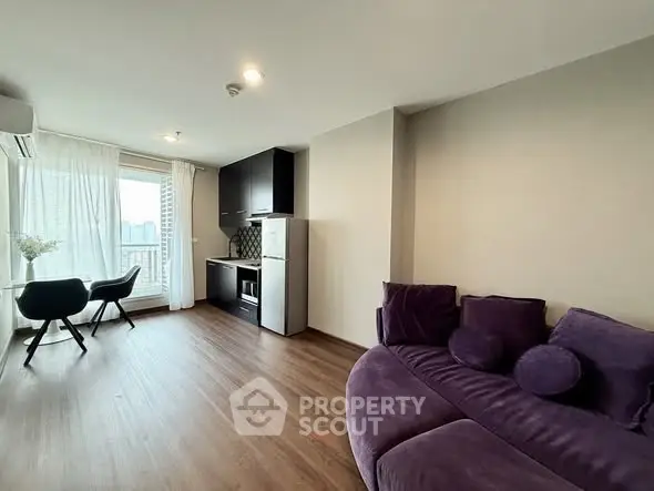 Modern living room with stylish purple sofa and compact kitchen area