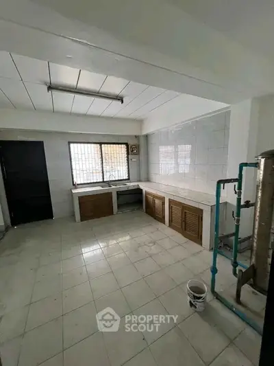 Spacious kitchen with tiled walls and ample natural light, featuring a closed layout and modern fixtures.