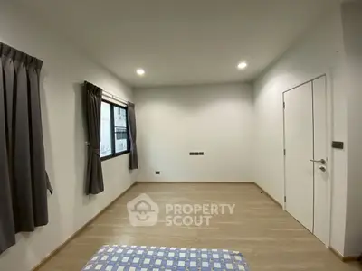Spacious bedroom with wooden flooring and modern lighting