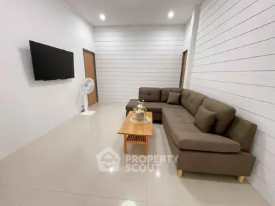 Modern living room with sleek sectional sofa and wall-mounted TV in minimalist design.