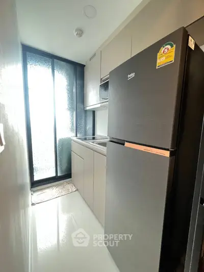 Modern kitchen with sleek appliances and minimalist design in a compact space.