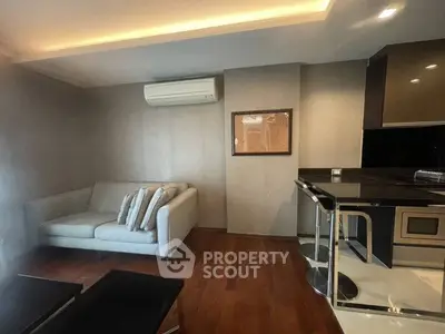 Modern living room with sleek design, featuring a cozy sofa, air conditioning, and stylish kitchen area.
