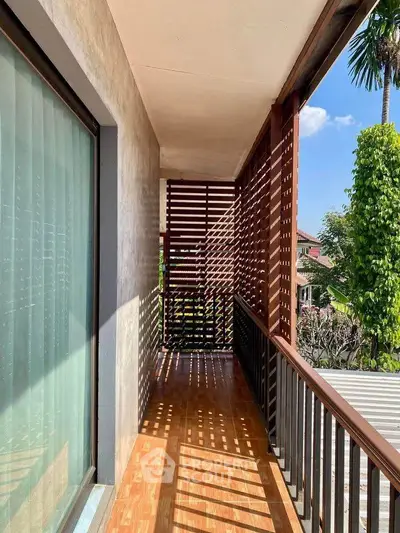 Charming balcony with wooden slats and lush greenery view, perfect for relaxation and enjoying nature.
