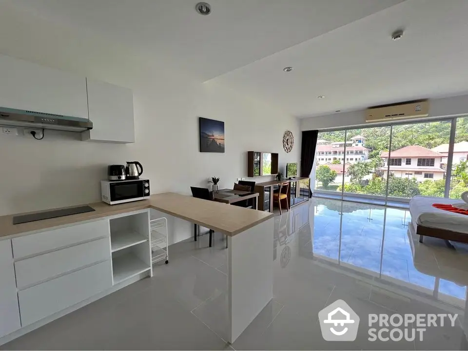 Modern open-plan living space with kitchen and large windows offering scenic views.