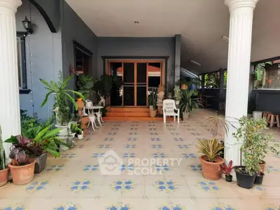 Charming entrance with tiled patio and lush greenery in a welcoming home setting.