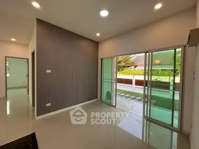 Spacious living area with sliding glass doors opening to a lush garden view.