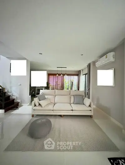 Spacious living room with modern decor, large comfortable sofa, and ample natural light, perfect for relaxation and entertaining guests.