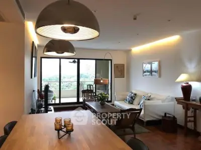 Spacious living room with modern decor and large windows leading to a balcony with a view.