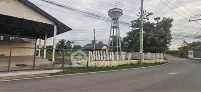 Scenic roadside view with water tower and fenced property, ideal for development.