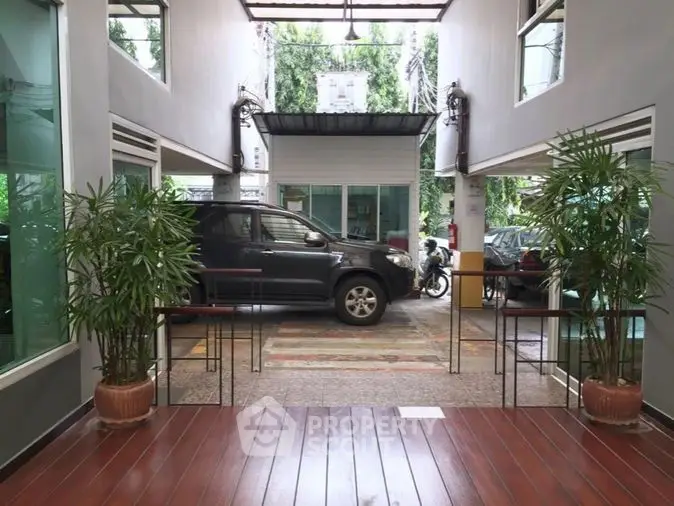 Modern building entrance with parking area and lush greenery