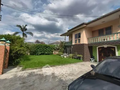 Charming two-story home with lush garden and spacious driveway under a cloudy sky.