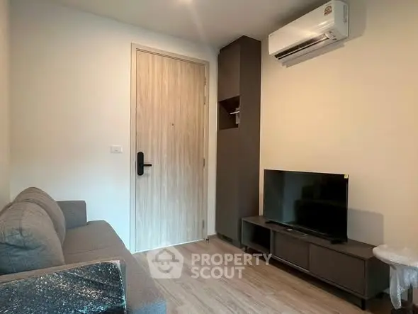 Cozy living room with modern sofa, TV, and air conditioning in a stylish apartment.