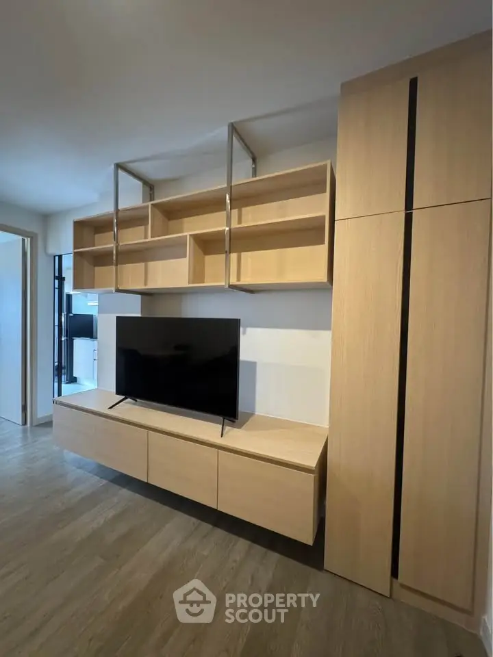 Modern living room with sleek wooden cabinetry and mounted TV, showcasing contemporary interior design.
