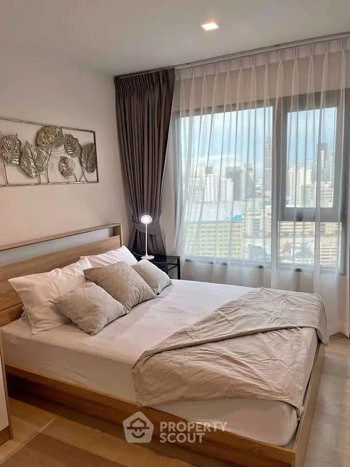 Modern bedroom with city view, stylish decor, and natural light in urban apartment.