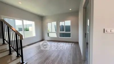 Spacious and bright interior with modern staircase and large windows, perfect for customization.