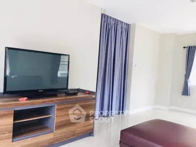 Spacious living room with modern TV setup and elegant curtains