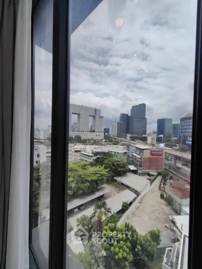 Stunning cityscape view from high-rise window showcasing modern architecture and lush greenery.