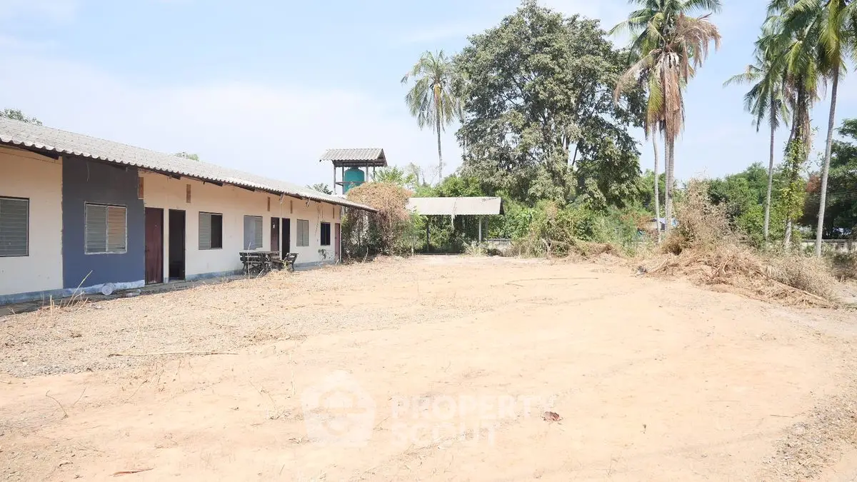Expansive land with potential for development, featuring a single-story building and lush greenery.