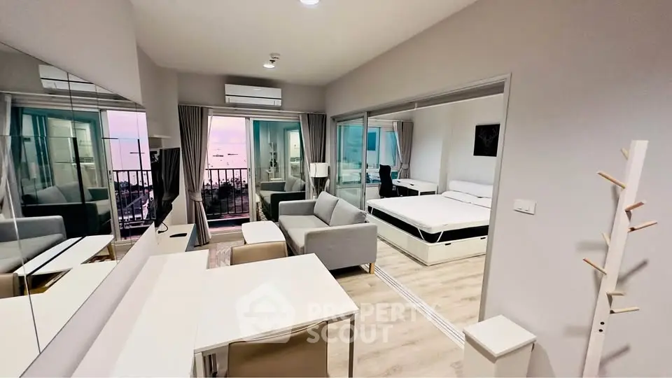 Modern studio apartment with balcony and sea view, featuring sleek interior design and open layout.