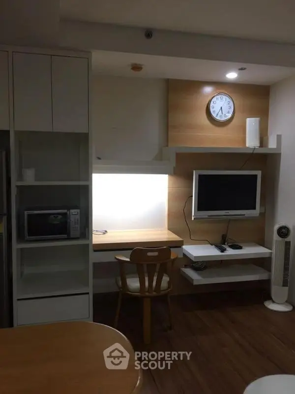 Modern study area with built-in shelves and wall-mounted TV in cozy apartment.