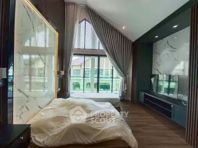 Luxurious bedroom with high ceilings and large windows offering a serene view.