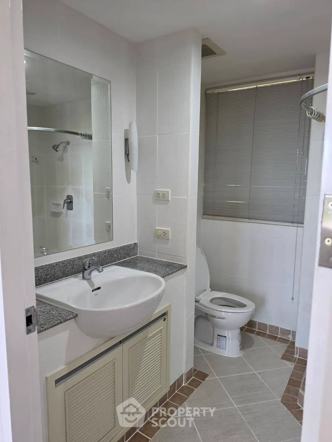 Modern bathroom with sleek fixtures and neutral tiles, featuring a large mirror and contemporary design.