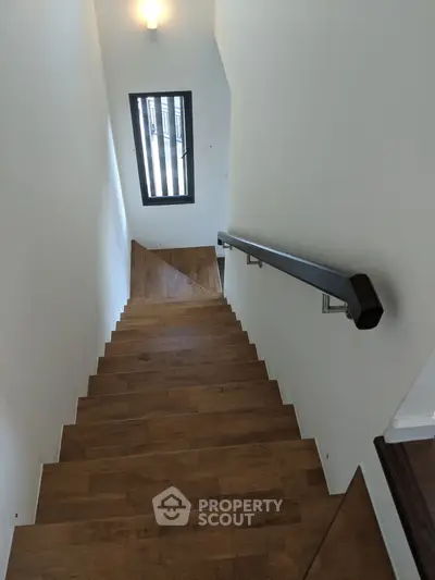 Elegant wooden staircase with modern railing and natural light from window