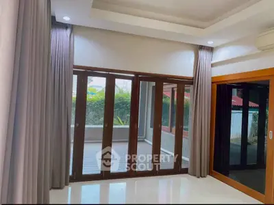 Spacious living room with large windows and garden view, perfect for natural light lovers.