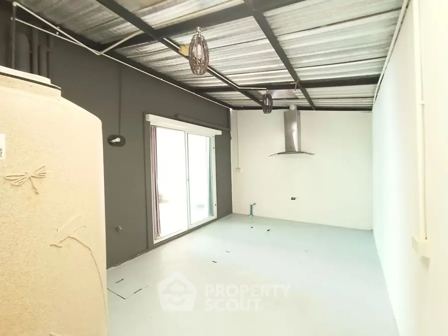 Spacious industrial-style room with metal ceiling and sliding glass doors.