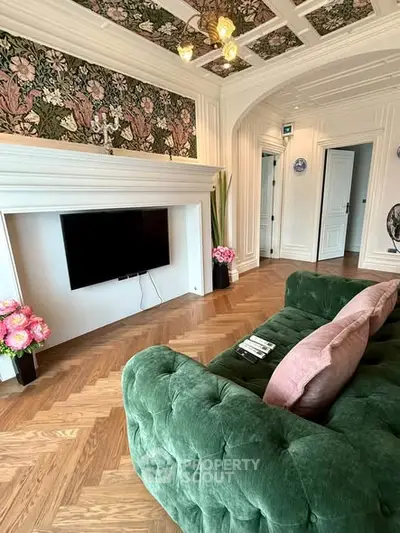 Luxurious living room with elegant green sofa, floral wallpaper, and mounted TV, showcasing exquisite interior design.