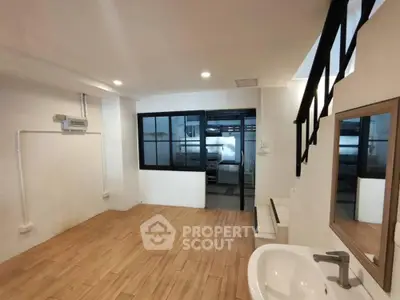 Spacious and modern bathroom with sleek white fixtures, large mirror, and warm wooden flooring, offering a serene and stylish retreat.