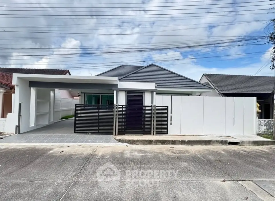Modern single-story house with sleek design and gated entrance in a suburban neighborhood.