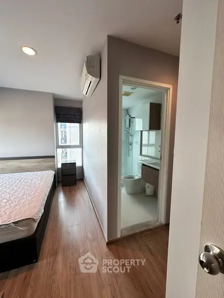 Modern bedroom with ensuite bathroom, featuring wooden flooring and natural light.