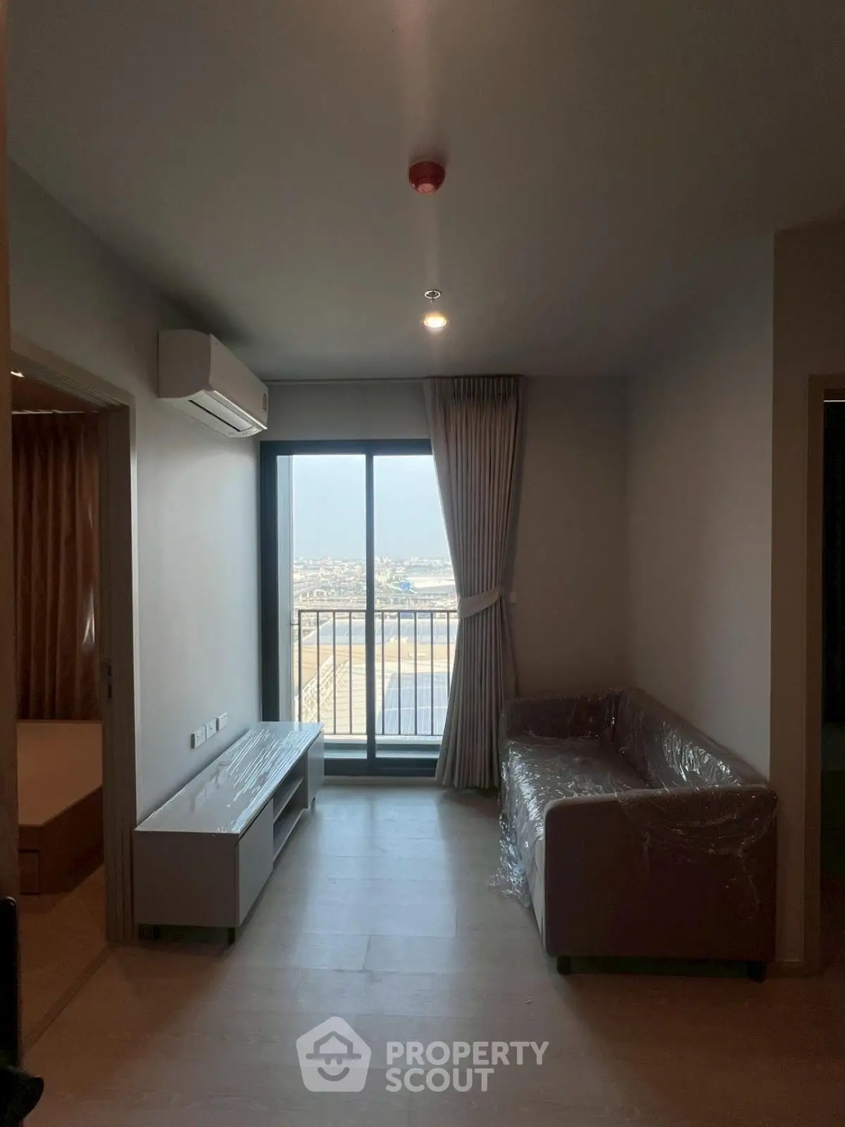Modern living room with balcony and scenic view, featuring sleek furniture and natural light.