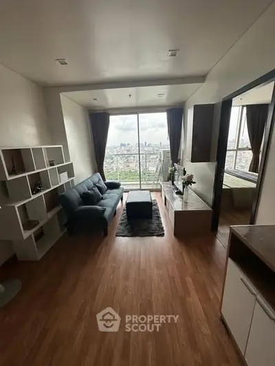 Modern living room with city view, featuring sleek furniture and wooden flooring.