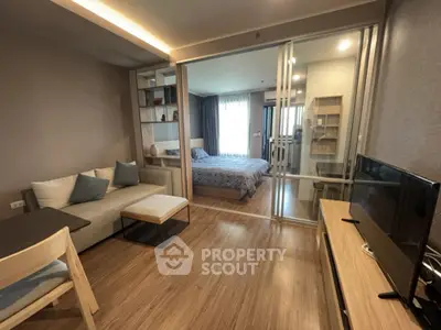 Modern open-plan living room with sliding glass doors to bedroom, featuring stylish decor and wooden flooring.
