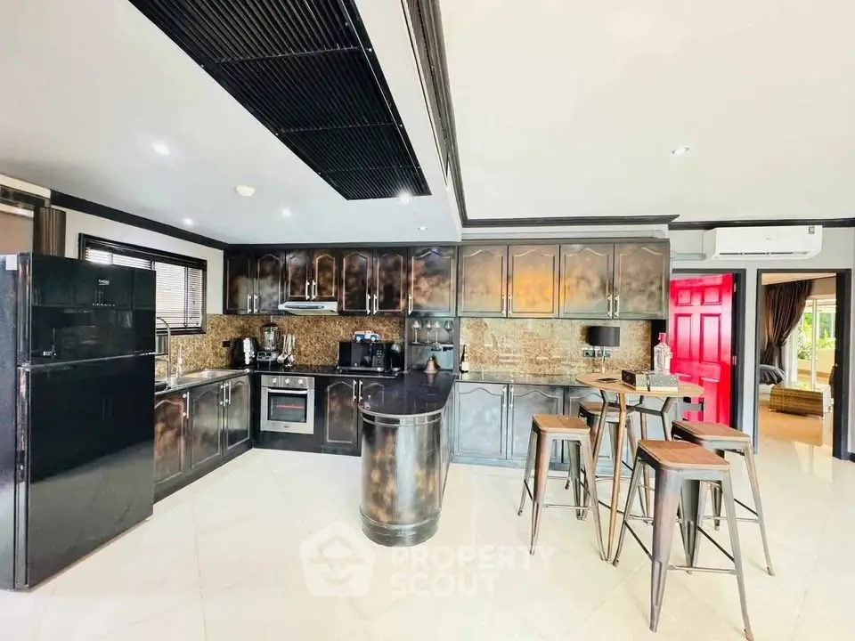 Modern kitchen with sleek black appliances and stylish bar seating in a contemporary home.