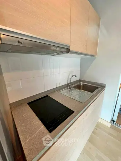 Modern compact kitchen with sleek countertop and built-in electric stove, ideal for urban living.