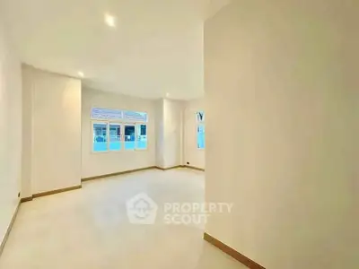 Spacious empty room with large windows and bright lighting, ideal for customization.