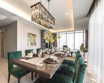 Luxurious dining room with elegant chandelier and plush green chairs in modern apartment.
