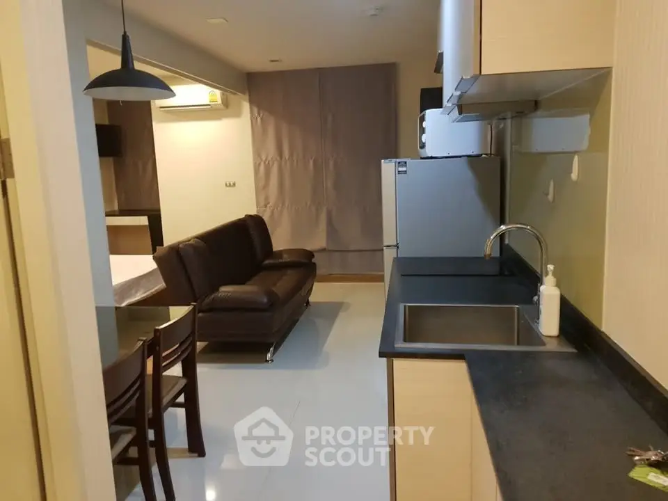 Modern apartment interior with open kitchen and cozy living area featuring sleek furniture.