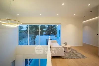 Modern living room with large windows and stylish lighting overlooking a serene outdoor view.