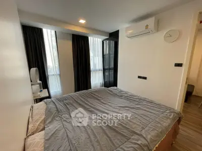 Cozy bedroom with modern decor and large windows in a stylish apartment.