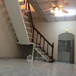 Spacious interior with unique staircase and ceiling fan, ideal for modern living.