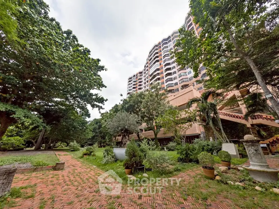 Lush garden view with towering residential building and brick pathway