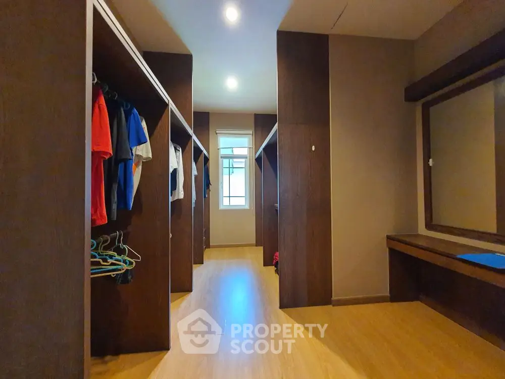 Spacious walk-in closet with wooden flooring and ample storage space.