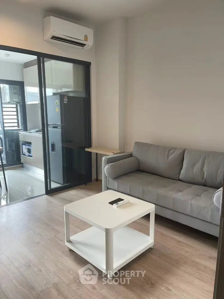 Modern living room with open kitchen and sleek furniture in a cozy apartment.